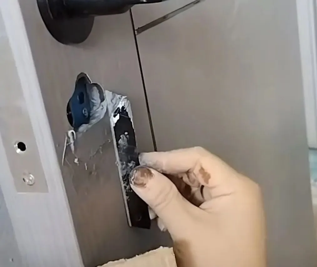 旧带面板酒店锁拆除后的房门现场：门板上留下超大的传统锁体孔洞与多处分离开孔，新锁孔位对不上，常规方案要么扩孔补洞要么换门
